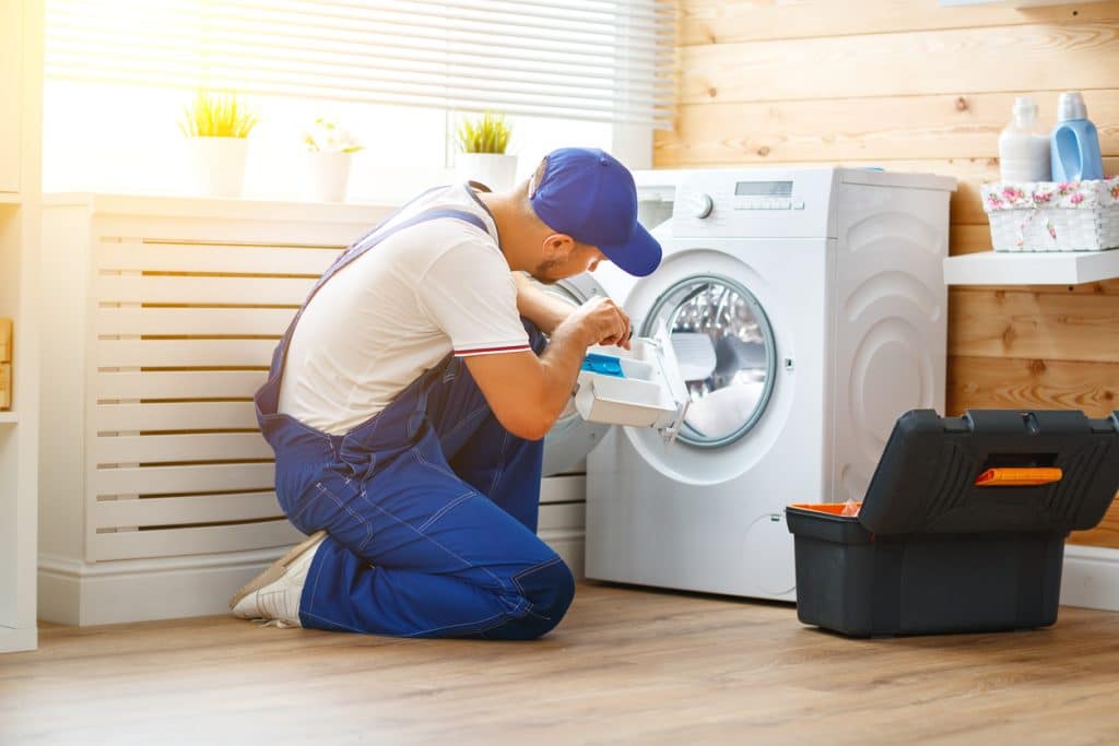 man repairs a washing machine
